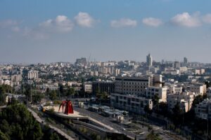 Urban area surrounded by greenery buildings and roads under sunlight and a cloudy sky
